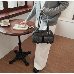 Detail of dark gray retro shoulder bag with two front pockets and gold metal buckles