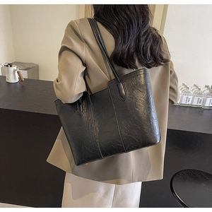 Detailed macro view of the black tote bag featuring retro pleated leather texture and straps