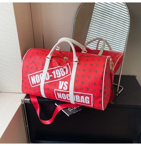 Dettaglio della borsa da viaggio rossa con logo, manici bianchi e tracolla regolabile