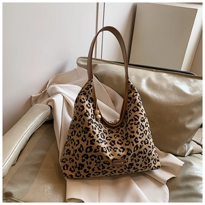 Close-up of leopard print tote bag with brand logo patch and round bead charm detail