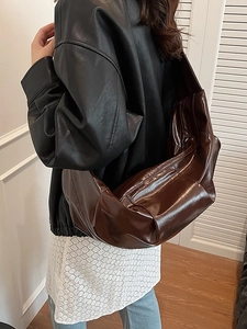 Brown hobo shoulder bag with pleated leather texture shown in a minimalist fashion style