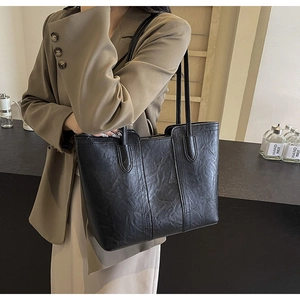 Detail of black faux leather tote bag with vintage wrinkled texture on brown blazer