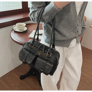 Close-up of a vintage black leather Boston bag featuring gold hardware and flap pockets