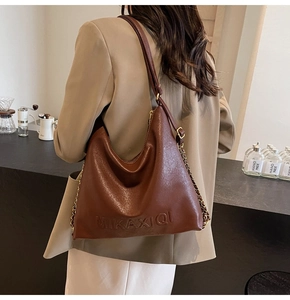 Dettaglio della borsa hobo in pelle marrone con logo a sbalzo e catena in metallo