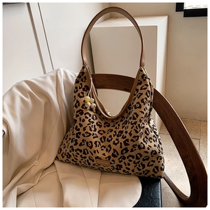 Close-up of leopard print tote bag with metallic brand plate and wooden bead charm detail