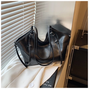 Detail of black faux leather tote bag with silver buckle and soft texture in soft light
