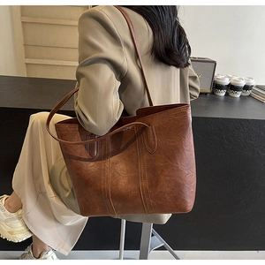 Detail of vintage brown tote bag featuring contrast stitching and soft faux leather texture