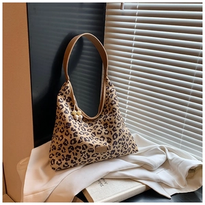 Detail of leopard print tote bag with brown strap and decorative bead charm on side