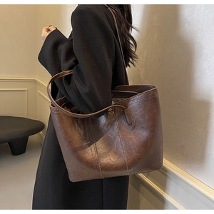 Detail of a large brown vintage faux leather tote bag with reinforced double shoulder straps