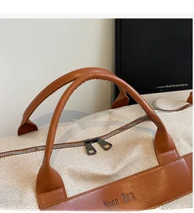 Close-up of woven canvas handbag featuring brown leather handles and dual metal zippers