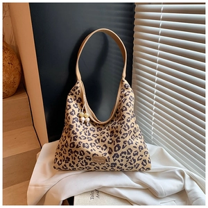 Close-up of leopard print shoulder bag with khaki leather strap and beaded charm
