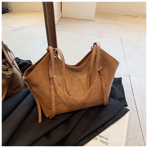 Detail of a brown winged tote bag featuring silver buckles and adjustable shoulder strap