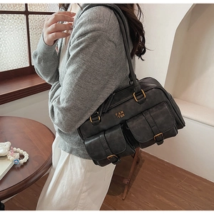 Detail of a vintage black leather underarm bag with double buckle front pockets and logo