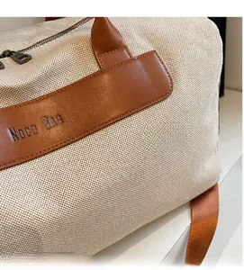 Close-up of beige canvas texture with brown leather logo strap and metal zipper detail