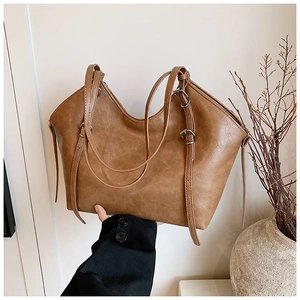 Detail of vintage brown tote bag with adjustable buckle straps and leather texture