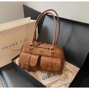 Brown vintage Boston bag with dual buckle pockets and metal logo on satin background