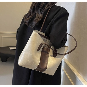 Detailed view of the large faux leather tote bag in beige and brown on a model shoulder