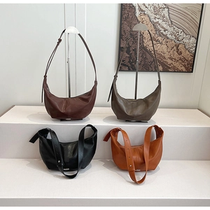 Detail view of crescent crossbody bags in brown, green, and black with wide straps