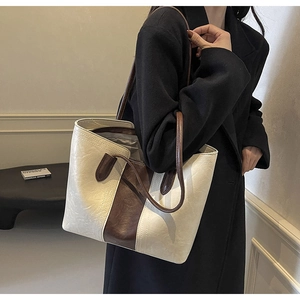 Close-up of retro cream and brown leather tote bag with fine stitching and zip detail