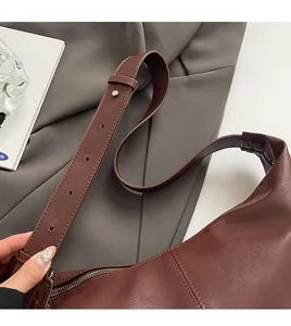 Close-up of adjustable wide shoulder strap with silver hardware on dark brown PU bag