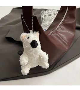 White fluffy bear pendant accessory on a vintage brown leather crossbody bag