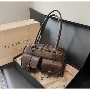 Detailed view of dark brown vintage shoulder bag with front pockets in a gift box setup