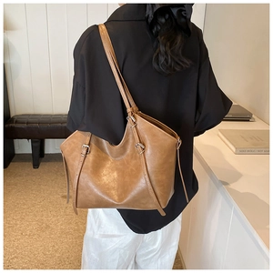 Detailed view of caramel brown tote bag with natural leather texture and metal buckles