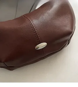 Close-up of premium dark brown lychee texture leather bag with silver metal buckle