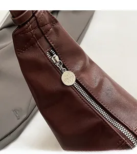 Close-up of high-quality silver metal zipper with round RICA logo on brown PU leather bag