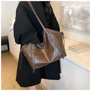 Detail of vintage brown tote bag showing side metal buckle straps and leather texture