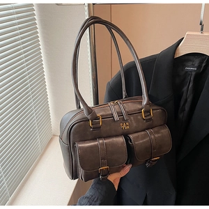 Close-up of retro brown leather shoulder bag with buckle pockets and metal logo detail