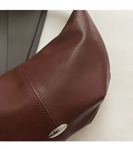 Detail of burgundy leather texture with silver oval buckle and precise stitching