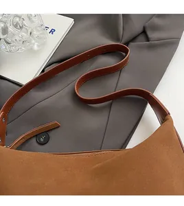 Detail of retro brown suede shoulder bag showing seamless comfort strap and soft texture