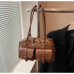 Detailed view of brown retro leather shoulder bag with two front pockets and twin handles