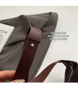 Detail of adjustable silver buckle on brown synthetic leather shoulder strap with multiple holes
