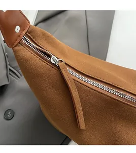 Detailed close-up of smooth silver metal zipper and brown suede texture on bag