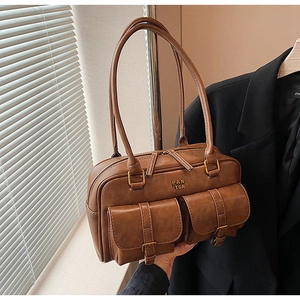 Close-up of brown PU leather shoulder bag with buckle pockets and metal logo detail