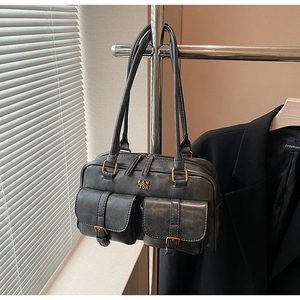 Detail of grey retro shoulder bag with two front buckle pockets and textured faux leather