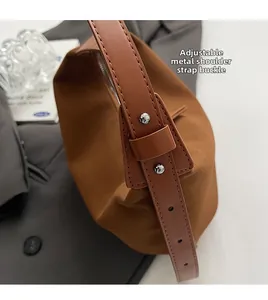 Detail of adjustable metal buckle on caramel leather strap of a vintage shoulder bag