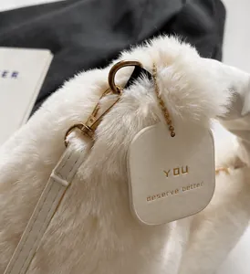 Detailed close-up of plush white handbag featuring polished gold hardware and logo tag