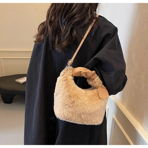 Detail of soft beige faux fur handbag with leather handle and adjustable strap on a coat