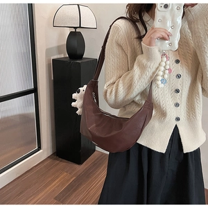 Brown faux leather crescent bag with shoulder strap and white plush dog charm detail