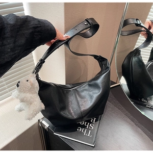 Detail of black semi-circle hobo bag with a white plush bear charm and adjustable strap