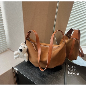 Close-up of brown matte suede crossbody bag with textured leather strap and plush bear charm
