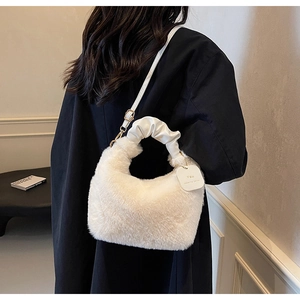 Detail of white faux fur handbag featuring a ruched handle and brand tag accessory
