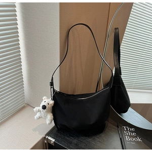 Minimalist black crescent shoulder bag featuring a cute white plush bear charm detail