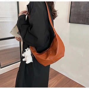 Caramel hobo shoulder bag with a cute white plush puppy charm and wide strap detail