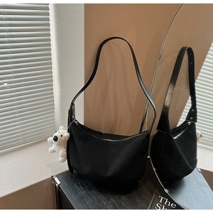 Mirror reflection showing details of a black hobo bag with a white plush puppy pendant