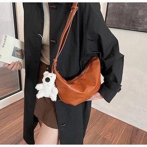 Close-up of brown vintage crossbody bag with soft faux leather and a cute plush bear charm