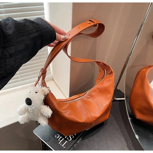 Detail of orange patent leather dumpling bag with plush bear charm and silver zipper
